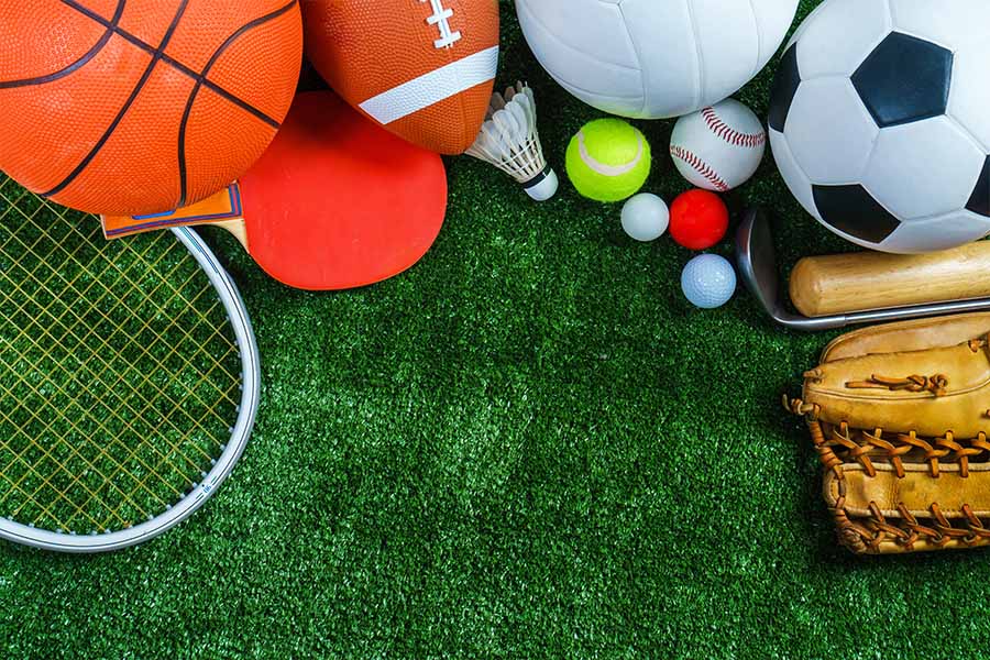 Sports Insurnace - Sports Equipment Laid Out in a Pile on the Green Grass on a Field